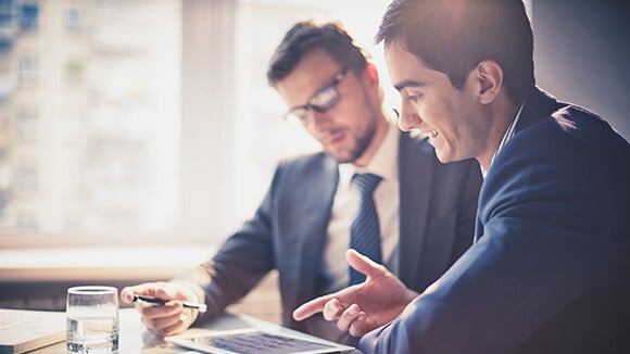 two man with tablet two man looking at a tablet in a meeting