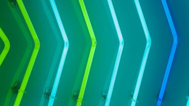 Groene en blauwe lichtbuizen gebogen in de vorm van een pijl