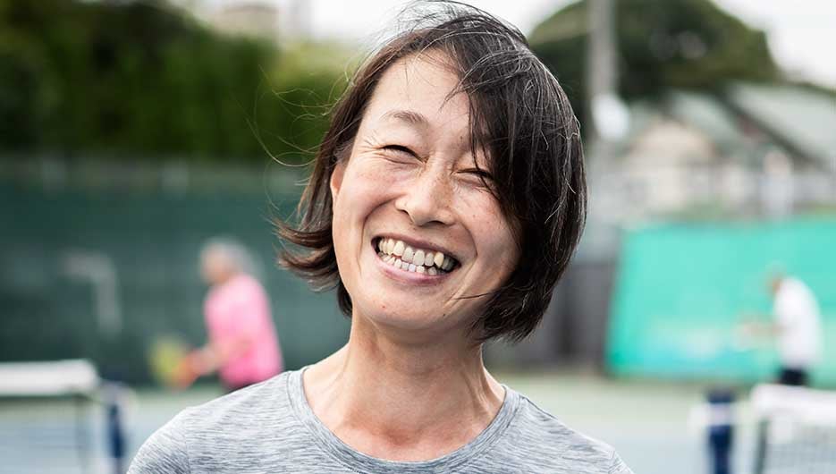 Women smiling on tennis court